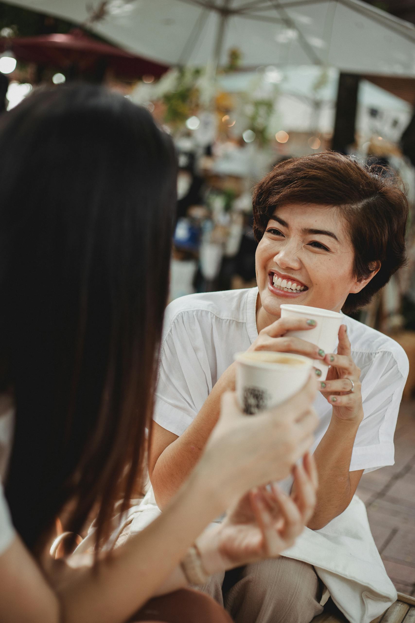 Two women enjoying a joyful coffee conversation outdoors at a café